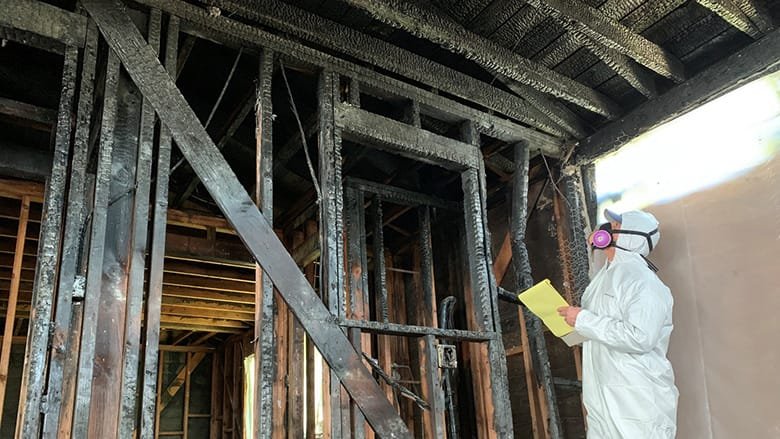 man inspecting fire damage on a house